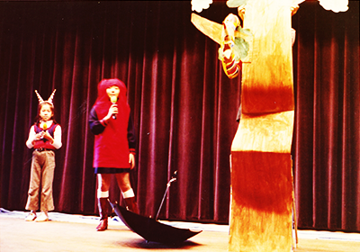 小学生の頃，初めての発表会で『だるまちゃんとかみなりちゃん』を英語で発表する筆者（中央：だるまちゃん役）